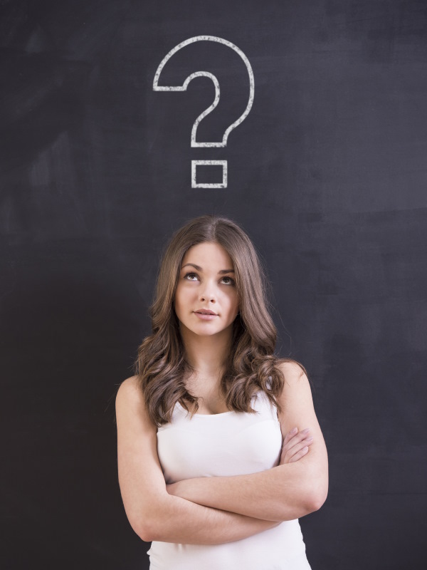 A shot of attractive young woman is standing in front of a blackboard with a question sign.